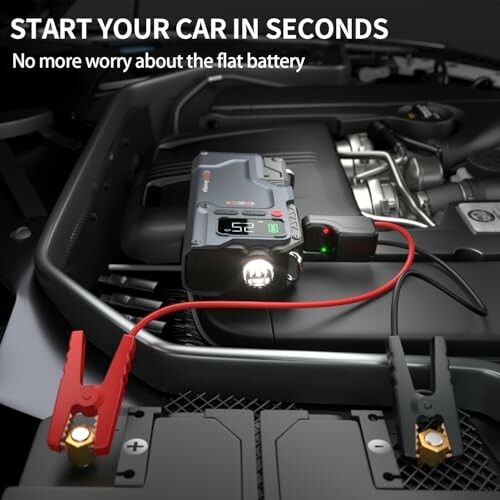 Portable car jump starter connected to battery.